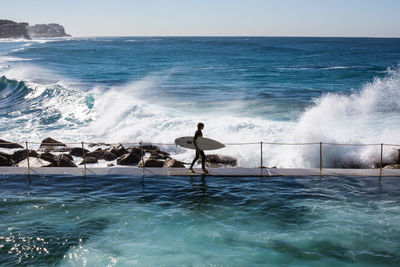 Side view of male surfer walking against the sea