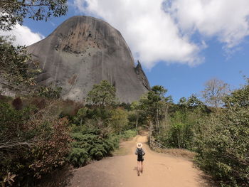 Rear view of man walking on mountain against sky