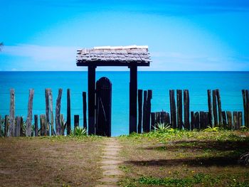 Wooden post by sea against clear blue sky