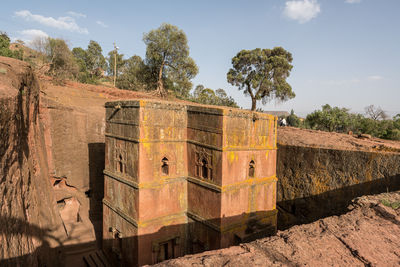 Old wall by building against sky