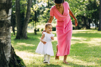 Rear view of women standing on grass against trees