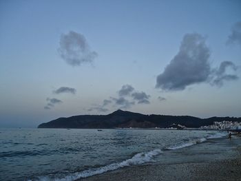 Scenic view of beach against sky at dusk