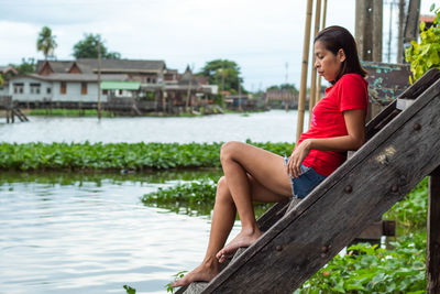 Side view of thoughtful woman sitting on steps by lake