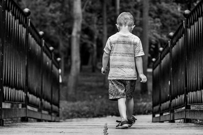 Rear view of man walking on footbridge