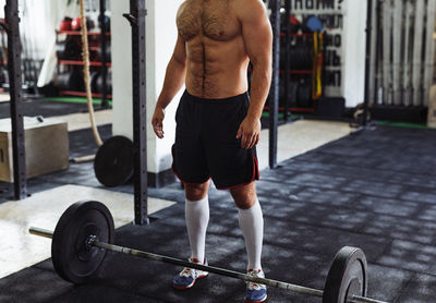 Low section of shirtless man standing at gym