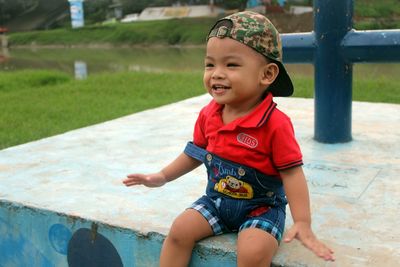 Close-up of cheerful baby boy sitting on seat outdoors