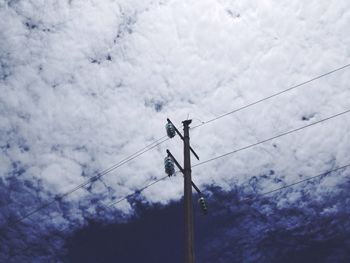 Low angle view of power lines against cloudy sky