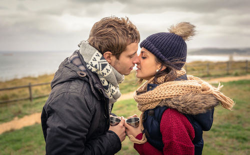 Young couple kissing against sky