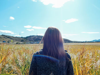 Rear view of woman standing on field against sky