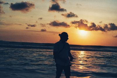 Man standing on beach against sky during sunset