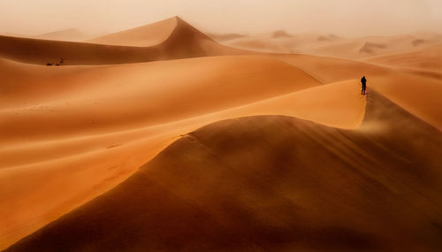 Person hiking on sand dunes in desert