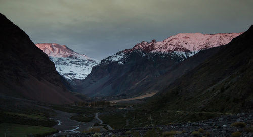 Snowcapped mountain range against cloudy sky