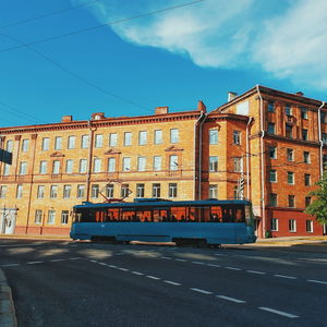 Road by building against blue sky