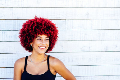 Portrait of smiling young woman against wall