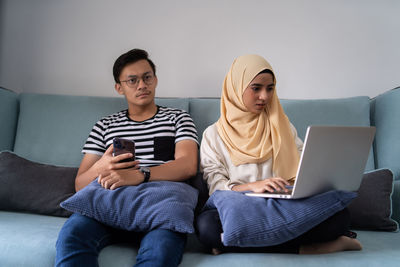 Man watching tv while woman sitting on sofa at home