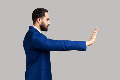 Side view of businessman with arms raised against white background