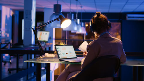 Rear view of woman using laptop at cafe