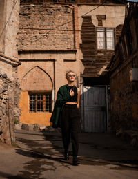 Portrait of young woman standing against old building