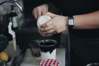 Midsection of man holding ice cream in kitchen