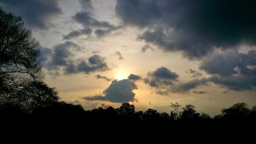 Low angle view of silhouette trees against cloudy sky