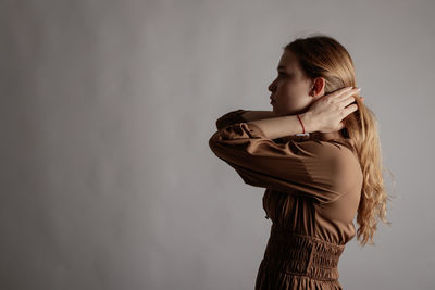 Side view of woman standing against wall