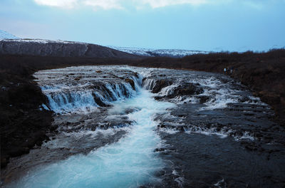 Scenic view of waterfall against sky