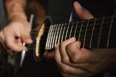 Midsection of man playing guitar