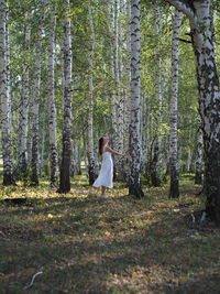 Rear view of woman standing in forest