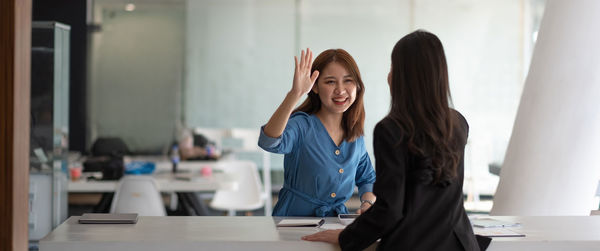 Smiling businesswoman giving high-five to colleague in office