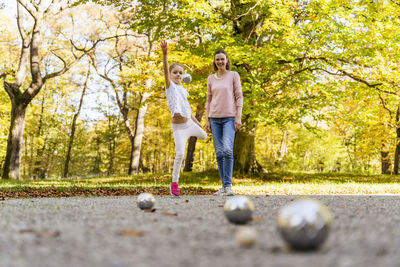 Happy mother and daughter playing boules in park