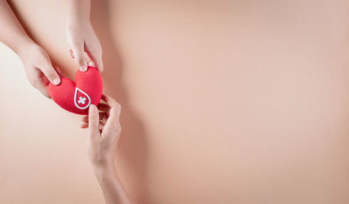 Midsection of woman holding red against white background