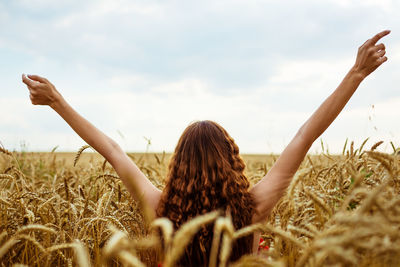 Female hands stick out from the wheat field. happy young