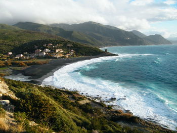 Scenic view of sea and mountains against cloudy sky