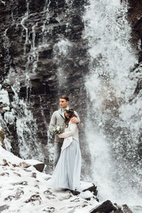 Full length of young man standing in waterfall