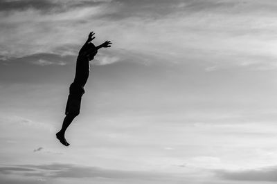 Low angle view of boy jumping against sky