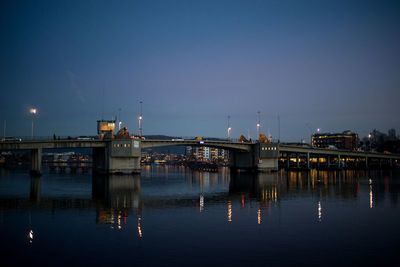 Boats moored at harbor against clear blue sky at night