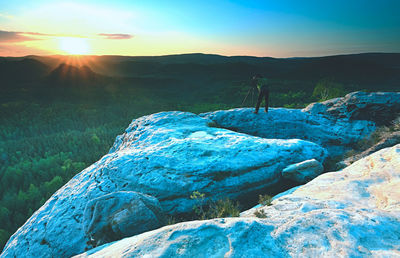 Photographer looks into the landscape. man prepare camera to takes impressive photos of misty fall