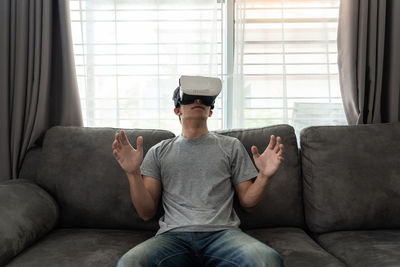 Midsection of man using mobile phone while sitting on sofa