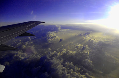 Cropped image of airplane flying over sea against blue sky