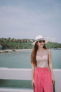 Young woman standing against lake