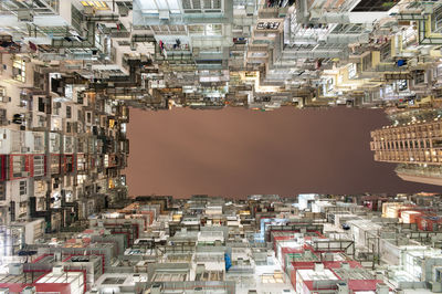 Directly below shot of buildings against sky in city at night