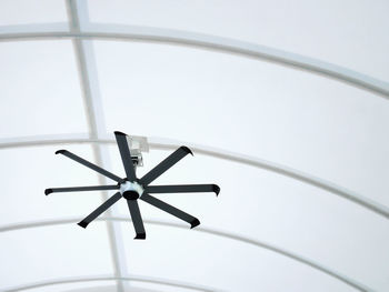 Low angle view of electric ceiling fan hanging under curved roof structure