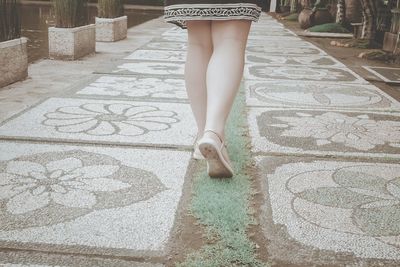 Low section of woman standing on footpath