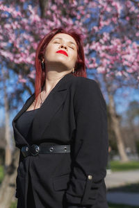 Young woman standing against trees