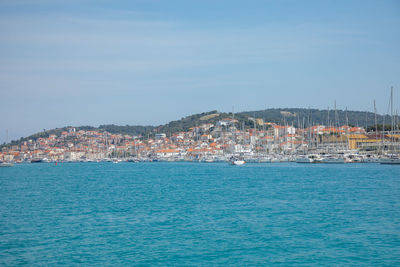 Scenic view of sea by townscape against sky