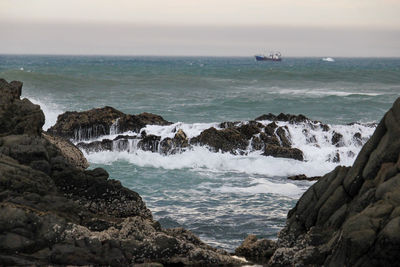 Scenic view of ocean waves breaking against the rocks 