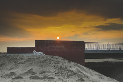 Man standing on beach against sky during sunset