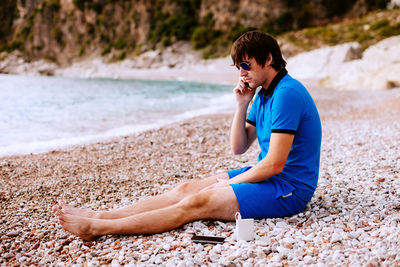 Side view of young woman sitting on beach