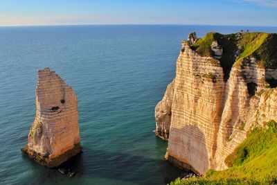 Rock formation by sea against sky