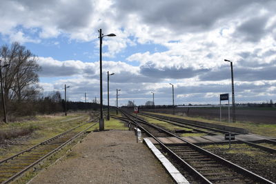 Railroad tracks by street against sky